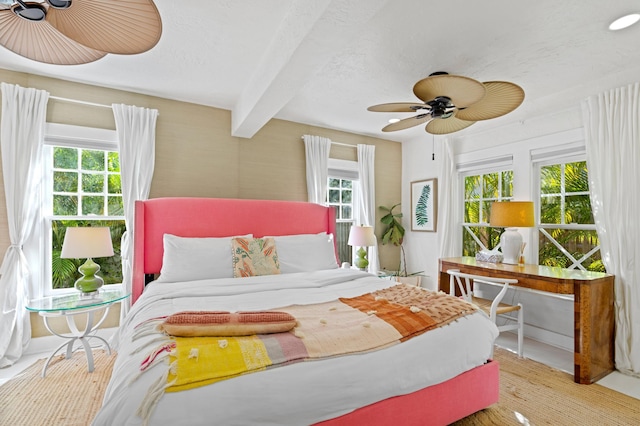 bedroom with ceiling fan, beam ceiling, light wood-type flooring, and multiple windows