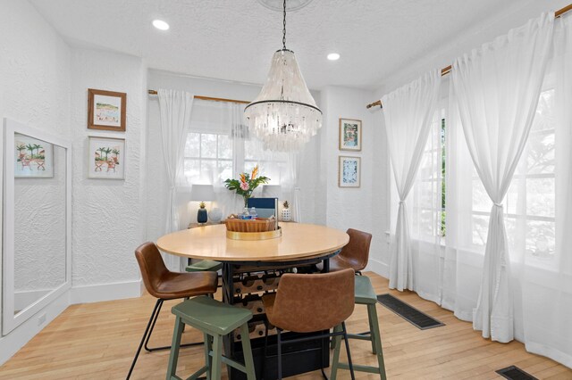 dining room with a chandelier, a textured ceiling, and light wood-type flooring