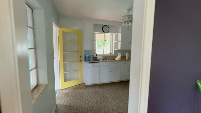 kitchen featuring ceiling fan, white cabinetry, and sink