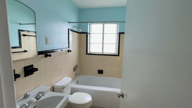 full bathroom featuring sink, tiled shower / bath combo, toilet, and tile walls