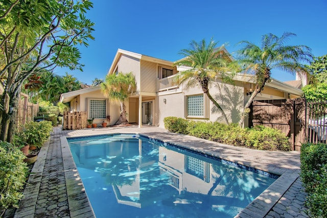 back of house with a balcony and a fenced in pool