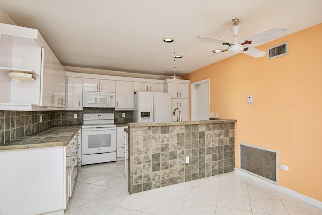 kitchen with white appliances, decorative light fixtures, white cabinetry, backsplash, and light tile patterned floors