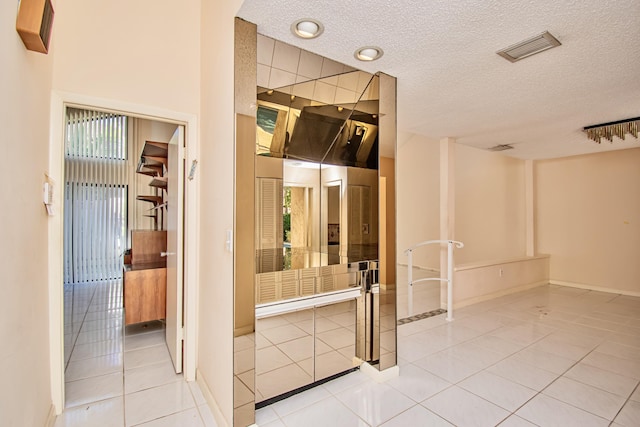 interior space featuring light tile patterned flooring and a textured ceiling