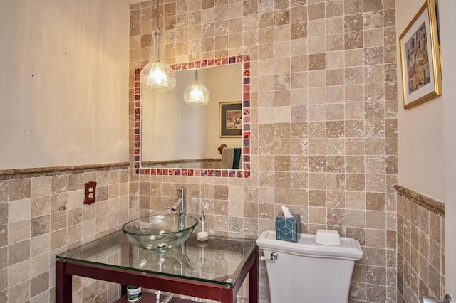 bathroom featuring toilet, tile walls, and sink