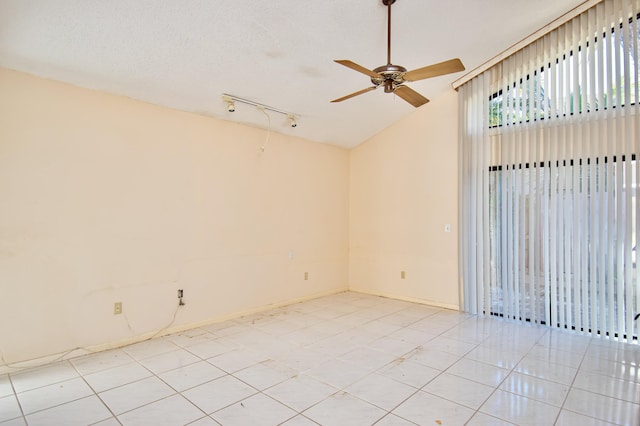 tiled empty room with vaulted ceiling, ceiling fan, and a textured ceiling