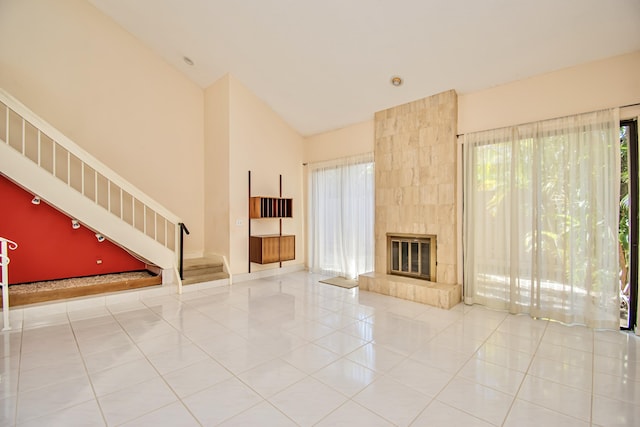 unfurnished living room featuring light tile patterned floors, a tile fireplace, and high vaulted ceiling