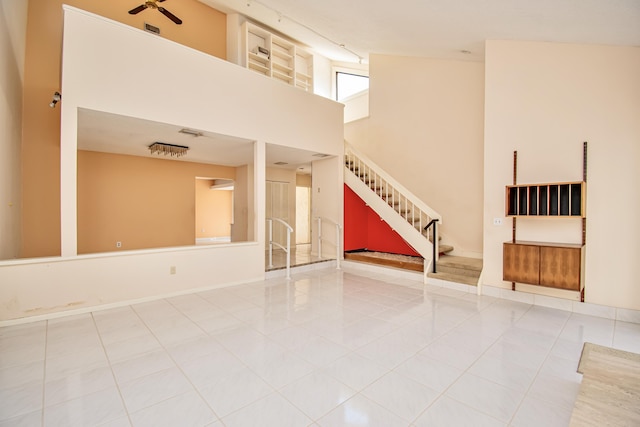 tiled spare room with ceiling fan and a high ceiling