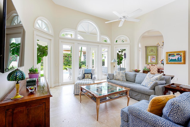 living room with ceiling fan with notable chandelier and a high ceiling