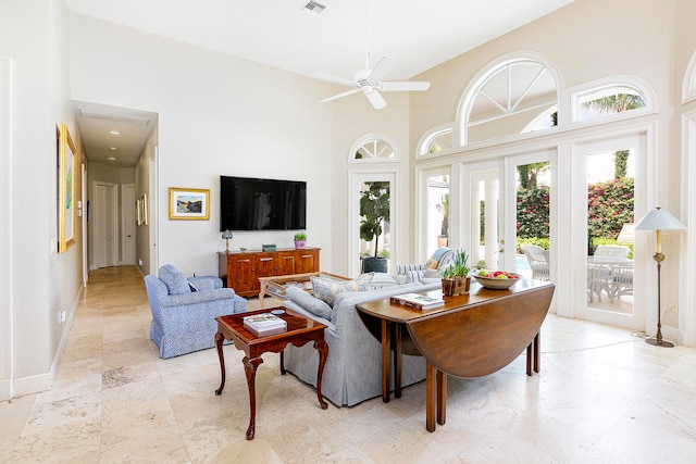 living room featuring ceiling fan, a high ceiling, and french doors