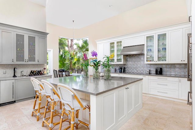 kitchen featuring a kitchen breakfast bar, a center island, backsplash, and exhaust hood