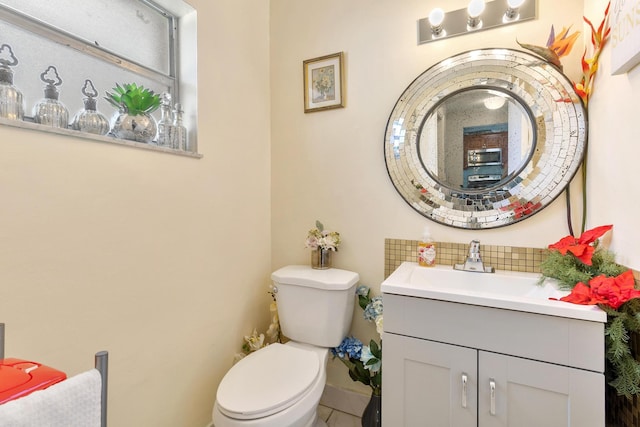 bathroom with vanity, toilet, and tasteful backsplash