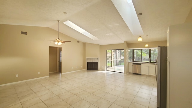 unfurnished living room featuring a tile fireplace, lofted ceiling with skylight, ceiling fan, and light tile patterned floors