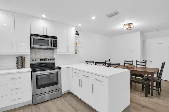 kitchen with kitchen peninsula, white cabinetry, light hardwood / wood-style flooring, and appliances with stainless steel finishes