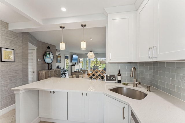 kitchen with kitchen peninsula, white cabinetry, and sink