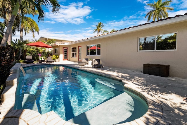 view of swimming pool with pool water feature and a patio area