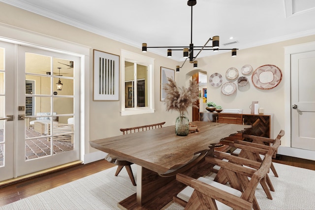 dining area featuring dark hardwood / wood-style floors, an inviting chandelier, and ornamental molding