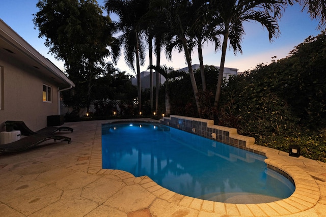 pool at dusk with a patio area