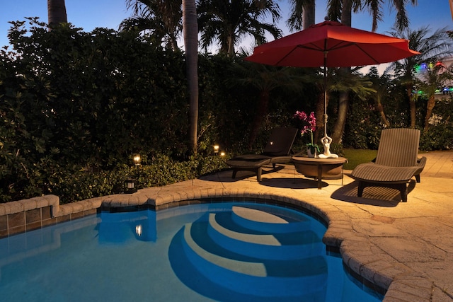 pool at dusk featuring a patio area