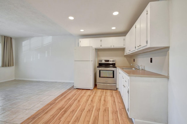 kitchen with stainless steel electric stove, sink, white refrigerator, white cabinets, and light hardwood / wood-style floors