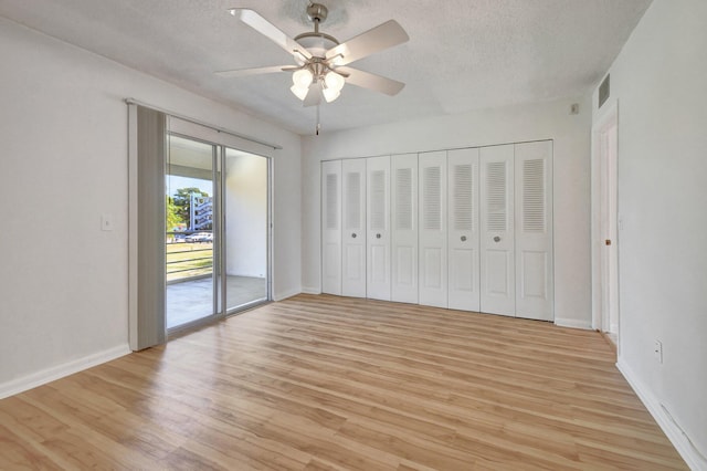 unfurnished bedroom featuring ceiling fan, a textured ceiling, access to outside, a closet, and light wood-type flooring