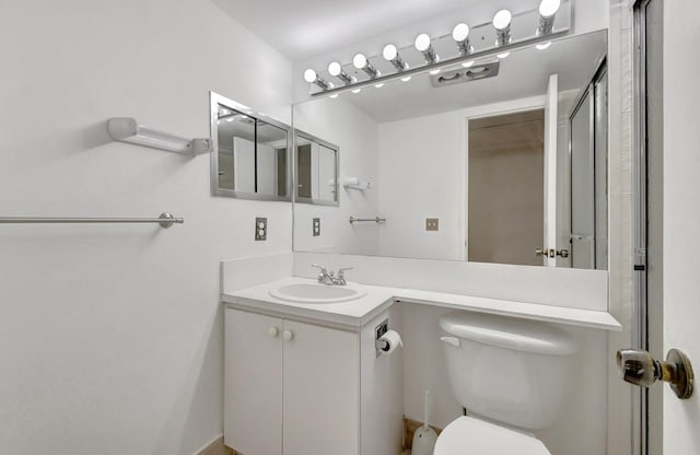 bathroom featuring a shower with door, vanity, and toilet