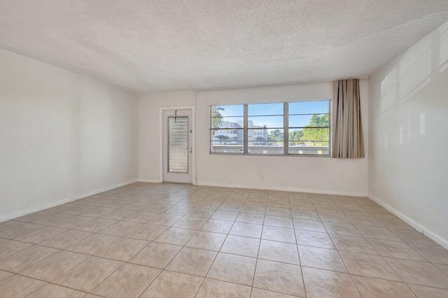 spare room featuring light tile patterned floors and a textured ceiling