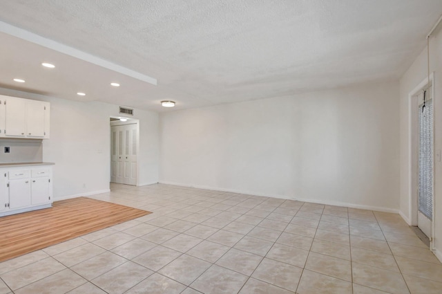 unfurnished living room with light tile patterned floors and a textured ceiling