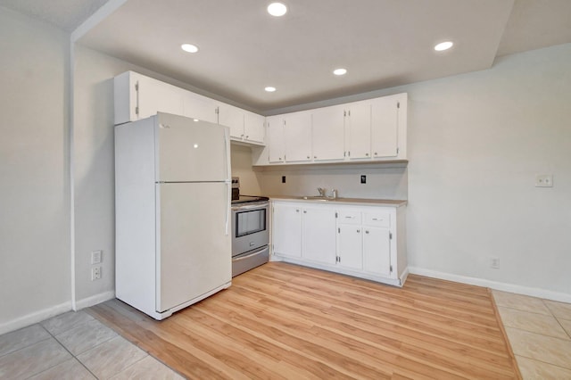 kitchen with electric stove, sink, light wood-type flooring, white fridge, and white cabinetry