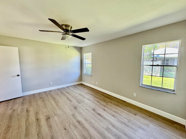 empty room with a textured ceiling, light wood-type flooring, and ceiling fan