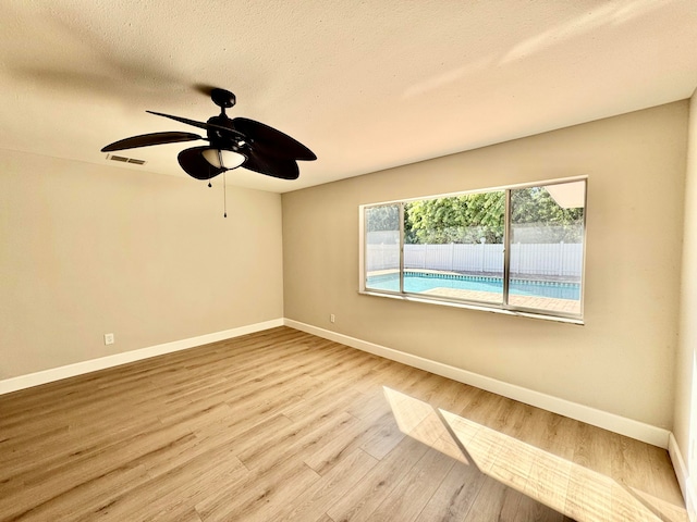 empty room featuring ceiling fan, light hardwood / wood-style floors, and a textured ceiling