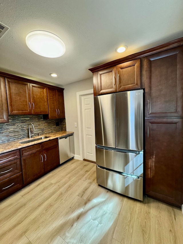 kitchen featuring decorative backsplash, sink, stainless steel appliances, and light hardwood / wood-style flooring