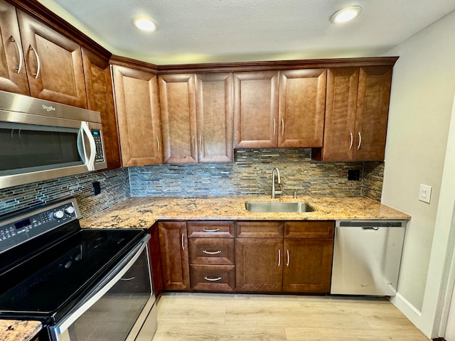 kitchen featuring light stone countertops, decorative backsplash, stainless steel appliances, and sink