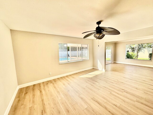 empty room with a textured ceiling, light wood-type flooring, and ceiling fan