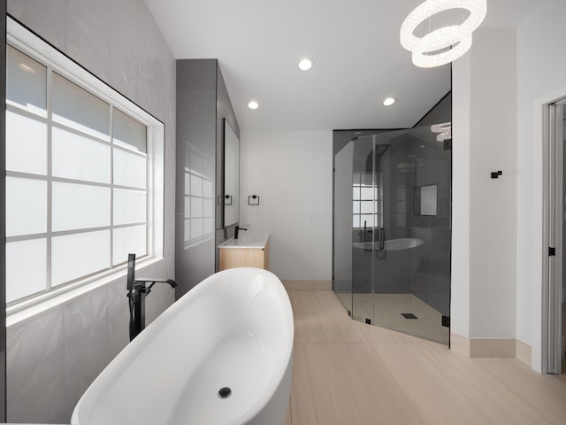 bathroom featuring independent shower and bath, vanity, and a chandelier