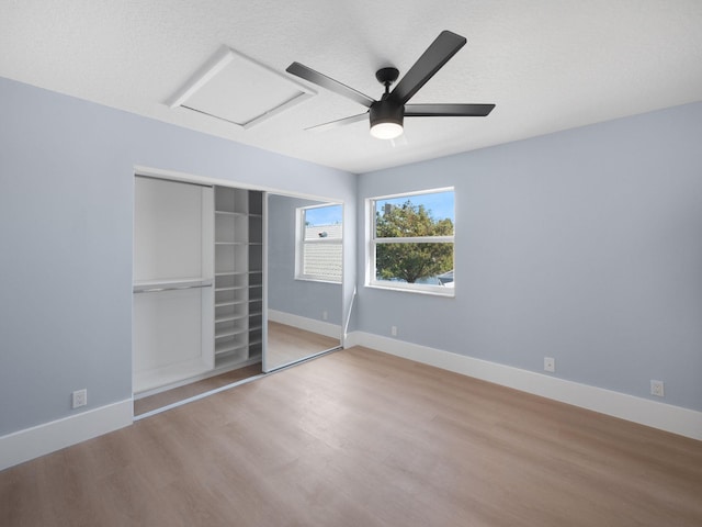 unfurnished bedroom with ceiling fan, a closet, light hardwood / wood-style floors, and a textured ceiling