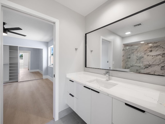 bathroom with tiled shower, vanity, hardwood / wood-style flooring, and ceiling fan