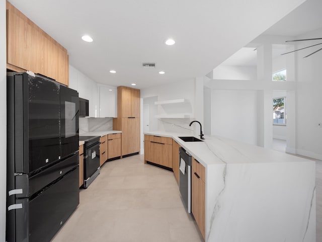 kitchen with kitchen peninsula, tasteful backsplash, light stone counters, sink, and black appliances