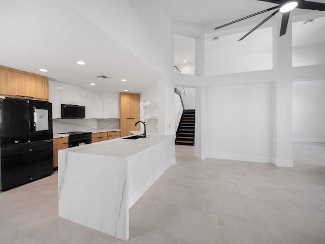 kitchen with decorative backsplash, sink, black appliances, a high ceiling, and white cabinetry