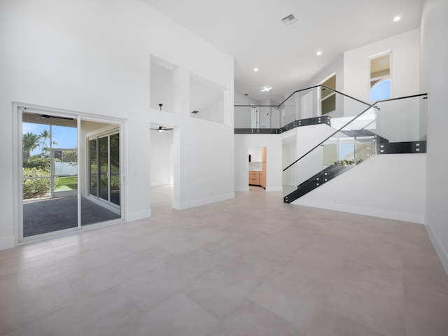 unfurnished living room featuring a towering ceiling