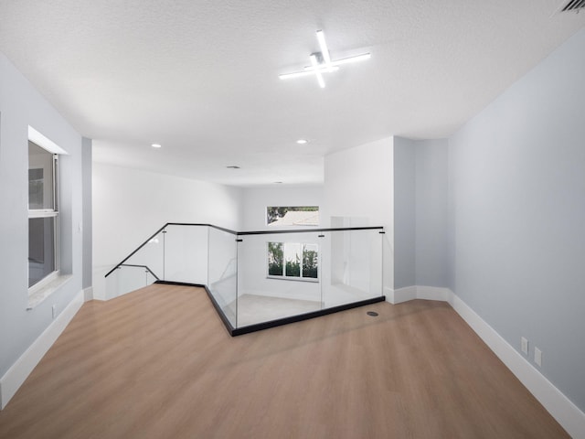 unfurnished room with light wood-type flooring and a textured ceiling