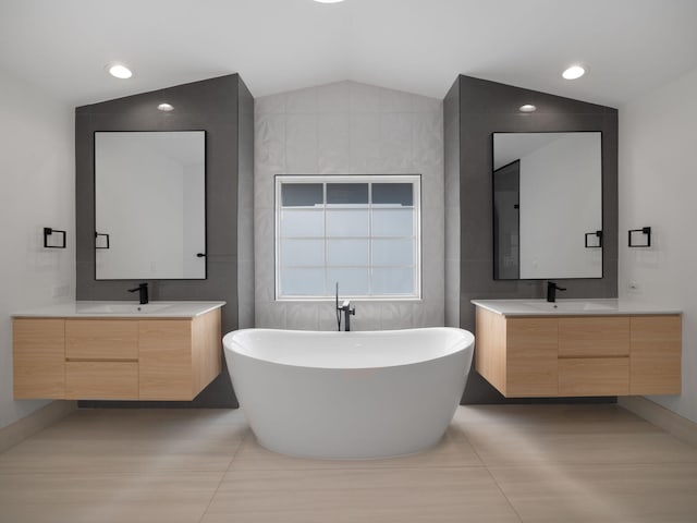 bathroom featuring a washtub, lofted ceiling, tile walls, and vanity