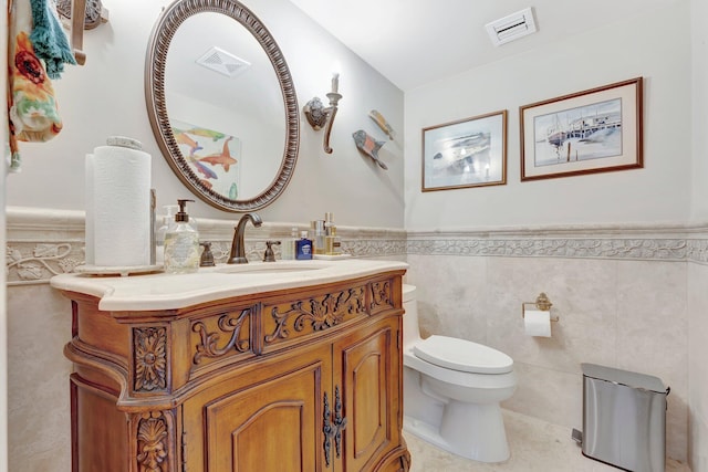 bathroom featuring tile patterned floors, vanity, toilet, and tile walls