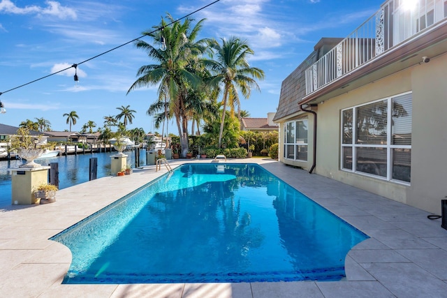 view of pool with a water view, a diving board, and a patio area