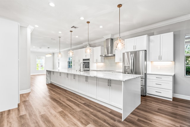 kitchen featuring wall chimney exhaust hood, stainless steel appliances, decorative light fixtures, white cabinets, and hardwood / wood-style floors