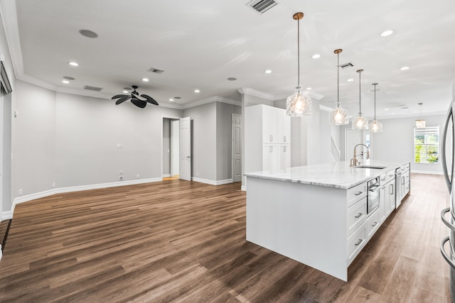 kitchen with a large island, sink, dark hardwood / wood-style floors, decorative light fixtures, and white cabinets