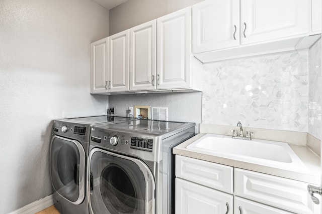 laundry room featuring washing machine and clothes dryer, cabinets, and sink