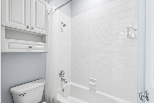 bathroom with tiled shower / bath combo and toilet