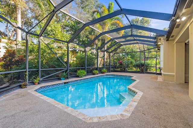 view of swimming pool with glass enclosure and a patio area