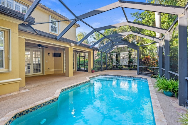 view of swimming pool with ceiling fan, a patio area, and glass enclosure