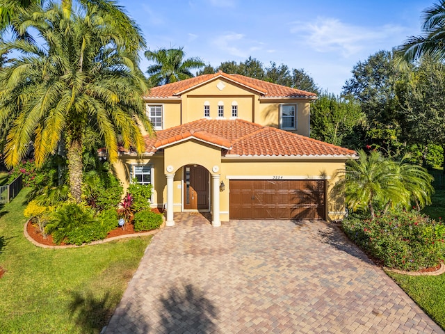 mediterranean / spanish-style house featuring a garage and a front lawn